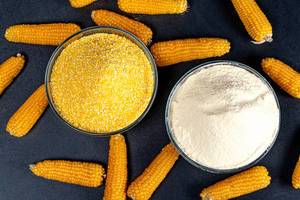 Top view, corn grits, flour and corn cobs on a black background