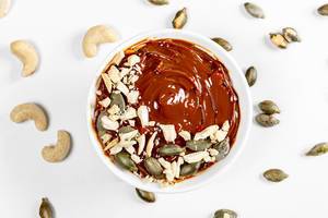 Top view dessert with condensed milk, cashews and pumpkin seeds on a white background