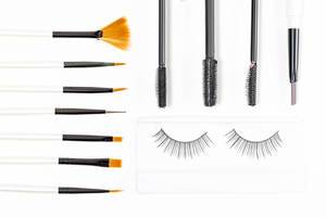 Top view, different cosmetic brushes, mascara brushes and false eyelashes on a white background