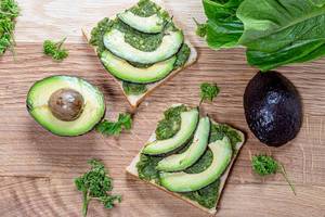 Top view fresh avocado sandwiches on wooden background with parsley greens (Flip 2019)