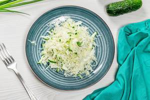 Top view fresh coleslaw in plate on white wooden background with fork