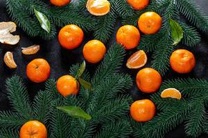Top view fresh tangerines with Christmas tree branches on black background (Flip 2019)