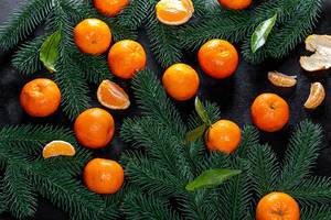 Top view fresh tangerines with Christmas tree branches on black background