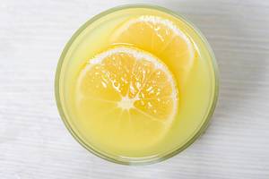 Top view glass of lemon juice with a slice of lemon on white wooden background (Flip 2019)