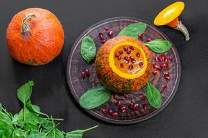 Top view Halloween concept-pumpkin with pumpkin puree, spinach and pomegranate on black background