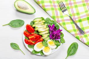 Top view healthy food background. Boiled eggs with fresh vegetables and spinach