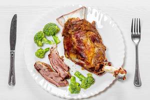 Top view lamb meat baked on a bone on a white plate with broccoli (Flip 2019)