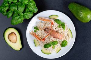 Top view, noodles with lobster, avocado and basil on a black background