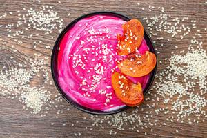 Top view-oatmeal with pink yogurt, sesame seeds and pieces of persimmon on a brown background (Flip 2019)