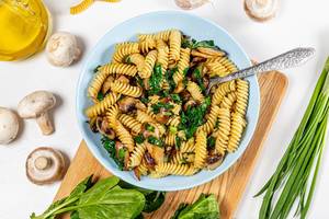 Top view of a bowl of pasta, mushrooms and herbs