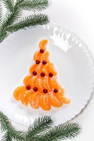 Top view of a Christmas tree made from mandarin and cranberries on a white plate (Flip 2019)