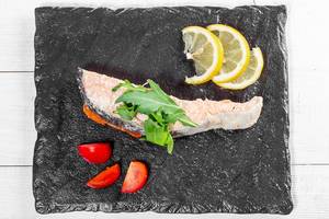 Top view of baked salmon with fresh arugula, lemon and tomatoes (Flip 2019)
