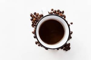 Top view of black coffee in a cup, net to beans