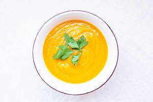 Top view of carrot cream soup topped with parsley