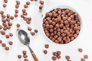 Top view of chocolate corn balls in bowl on white background