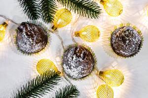 Top view of chocolate cupcakes with christmas tree branches and a luminous garland (Flip 2019)