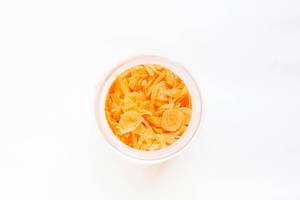 Top view of chopped carrots in jar on white background