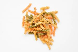 Top view of colored pasta fusilli on white background