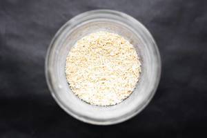 Top view of dried white onion spice in jar on dark background