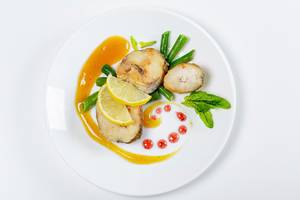 Top view of fish with asparagus, lemon and mango sauce