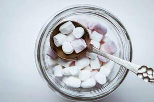 Top view of mini marshmellows in a jar with vintage spoon