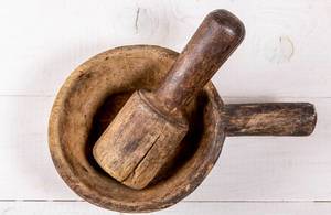Top view of old wooden mortar and pestle on white wooden background