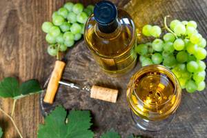 Top view of ripe grapes and white wine in bottle and glass on old wooden background (Flip 2019)