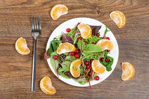 Top view of salad with spinach, Mandarin orange and cranberries on a wooden background (Flip 2019)