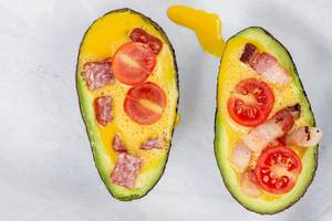 Top view of sliced Avocado with eggs meat and tomato ready for baking (Flip 2019)