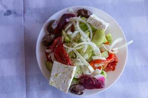 Top view of traditional Greek salad with peppers, cucumbers, onions, olives and feta cheese