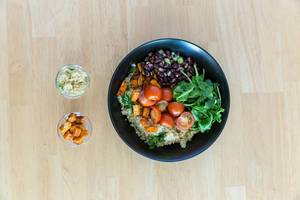 Top view of veggie bowl with sweet potatoes, cherry tomatoes, rocket and red beans