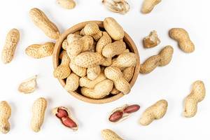 Top view, peanuts in a wooden bowl on a white background (Flip 2020)