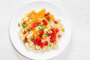 Top view porridge couscous on a white plate with vegetables