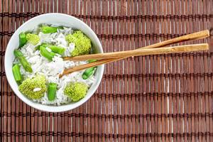 Top-view Reis mit Brokkoli und Spargel in einer Schale und Essenstäbchen