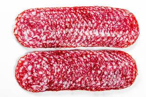 Top view sliced smoked salami on white background