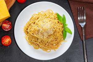 Top view spaghetti with cheese, sesame seeds and Basil leaves on a black background