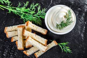 Top view white sauce and crackers with fresh dill on black stone background (Flip 2019)