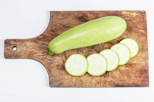 Top view, whole and sliced zucchini on a kitchen board