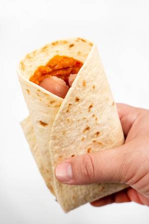 Tortilla with Sausages in the hand above white background (Flip 2020)