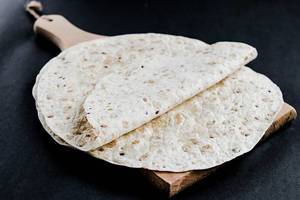 Tortilla wraps on wooden board on dark background