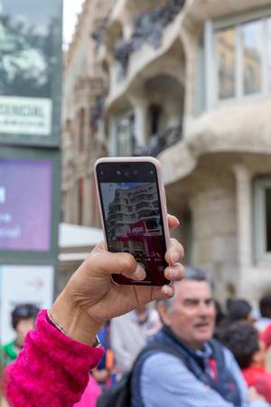 Tourist schießt ein Handyfoto von Designerhaus und Kulturstätte Casa Milà in Spaniens Hauptstadt Barcelona