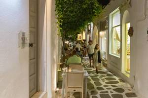 Touristen in typischer, Gasse mit Tischen in der Küstenstadt Naoussa auf Paros