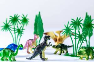 Toy dinosaurs and trees on white background