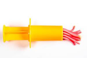 Toy pastry yellow syringe and dough on a white background