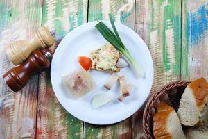 Traditionelles Frühstuck aus der Balkanküche mit Schweinefleisch in Aspik und Speck vor einem Retro-Hintergrund