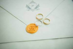 Trauringe und Verlobungsring auf mit Siegel verschlossener Hochzeitseinladung