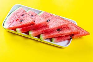 Triangular pieces of ripe red watermelon on a yellow background