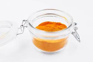 Turmeric powder in a jar on white background