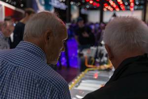 Two elder men looking at the e-tron drivetrain for all-electric vehicles by Audi