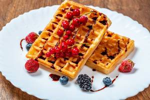 Two fried Belgian waffles with fresh fruit and chocolate syrup